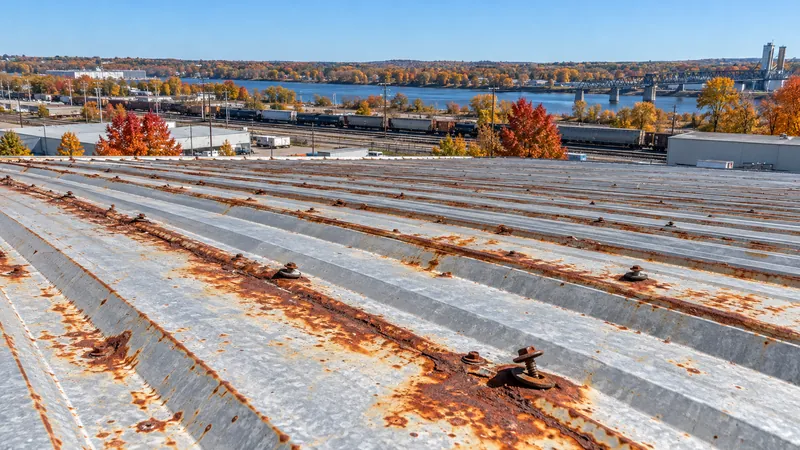 Rust bloom and corroded fastener heads along the ribs of old metal roof panels